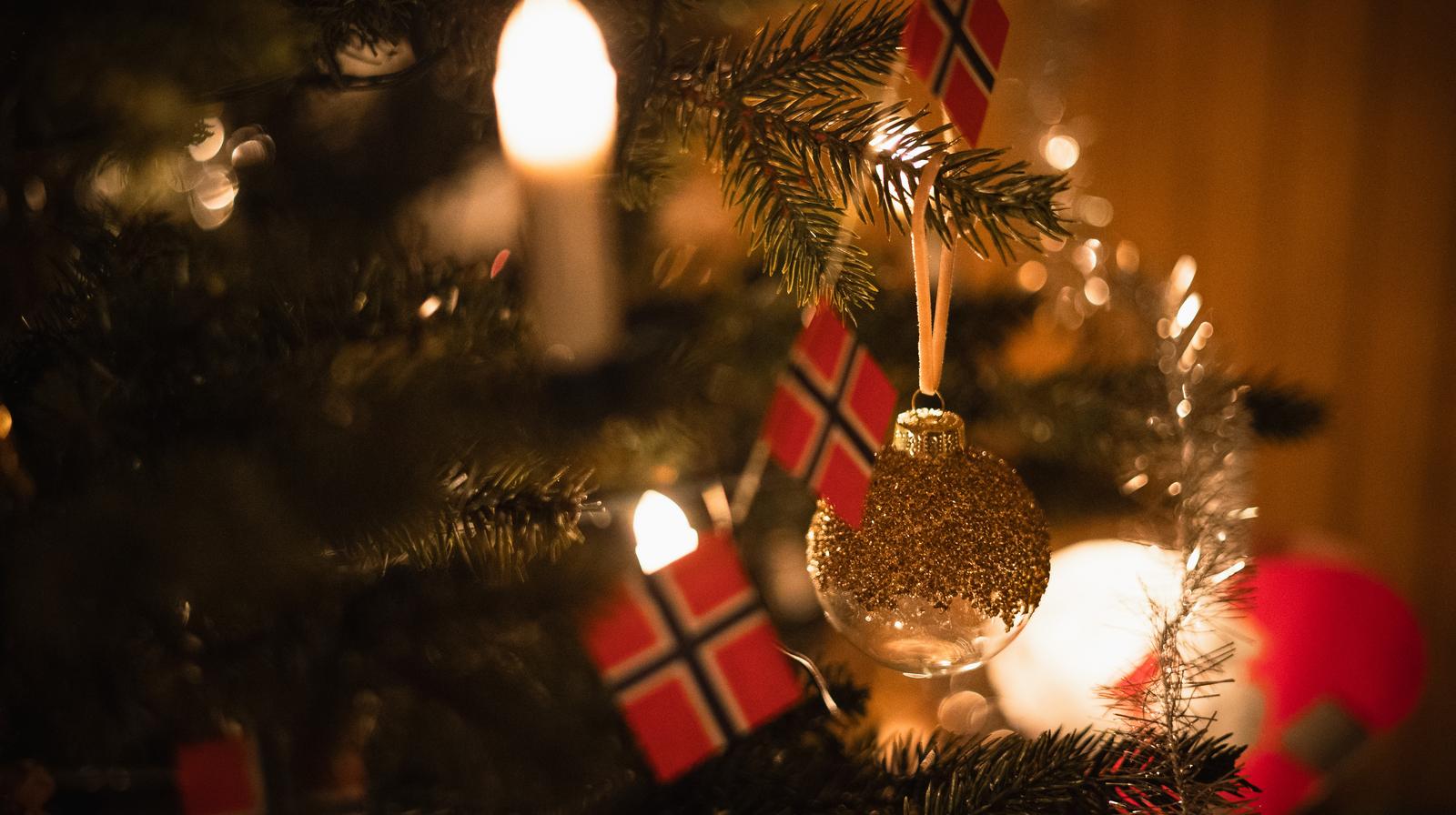Nærbilde av juletre pyntet med lys, glitter, norske flagg og julekule